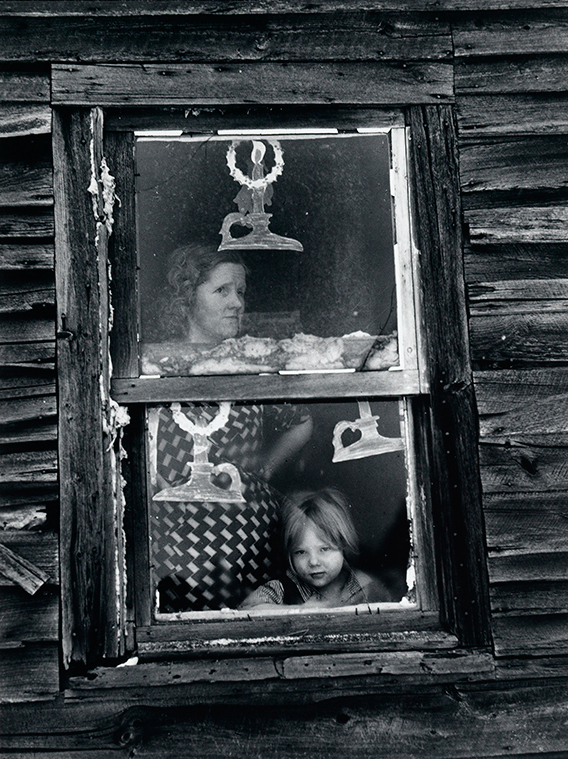 Arthur Weinstein's photograph, Wife and child of sub-marginal farmer at their window decorated for Christmas, Oswego County, New York