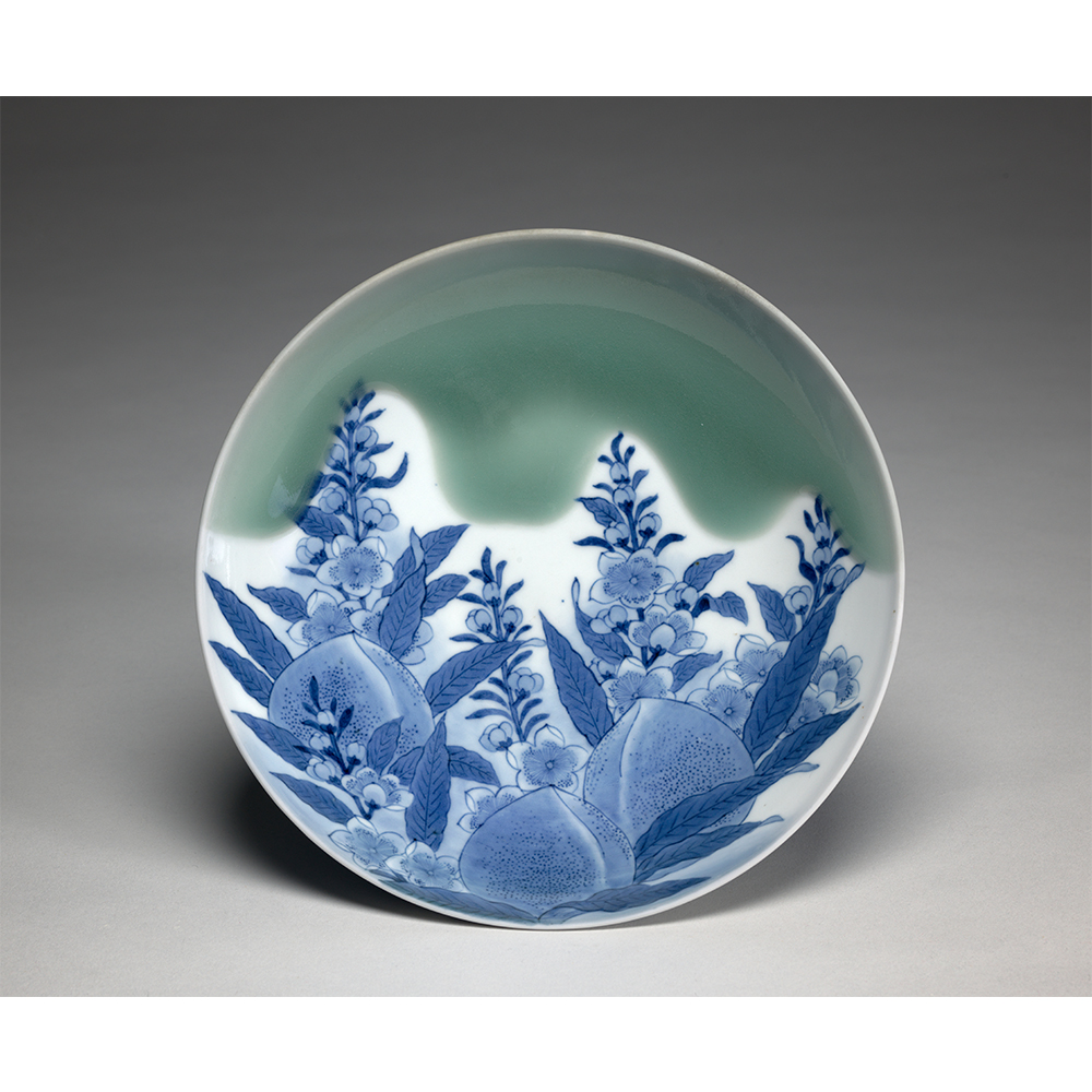 Plate sized dish with designs of peaches and bellflowers in blue and green. 