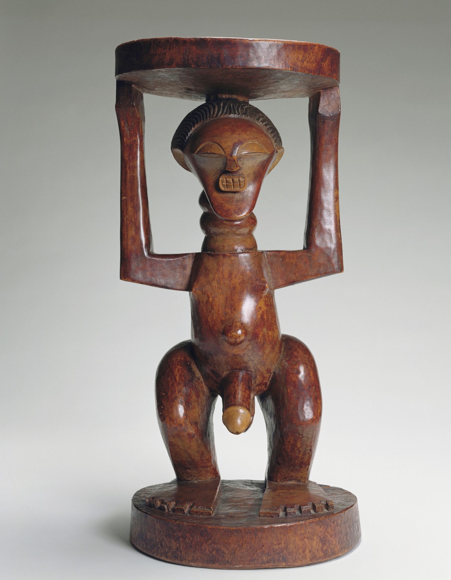 Wooden stool carved in figure of a naked person holding up the seat