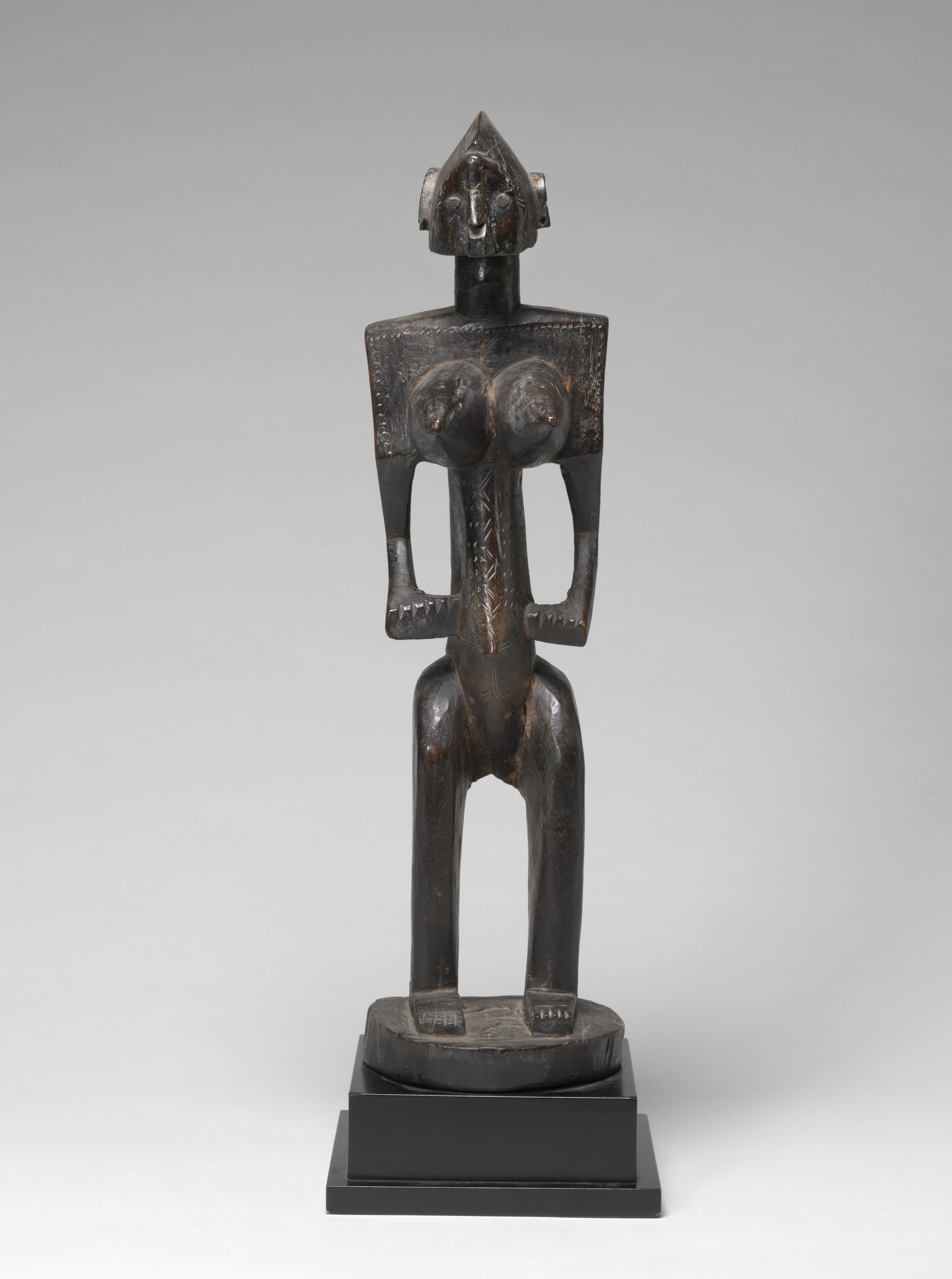 Wood and metal sculpture of a figure standing. 