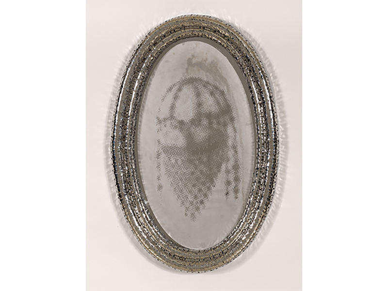 Oval mirror with faded image inside.