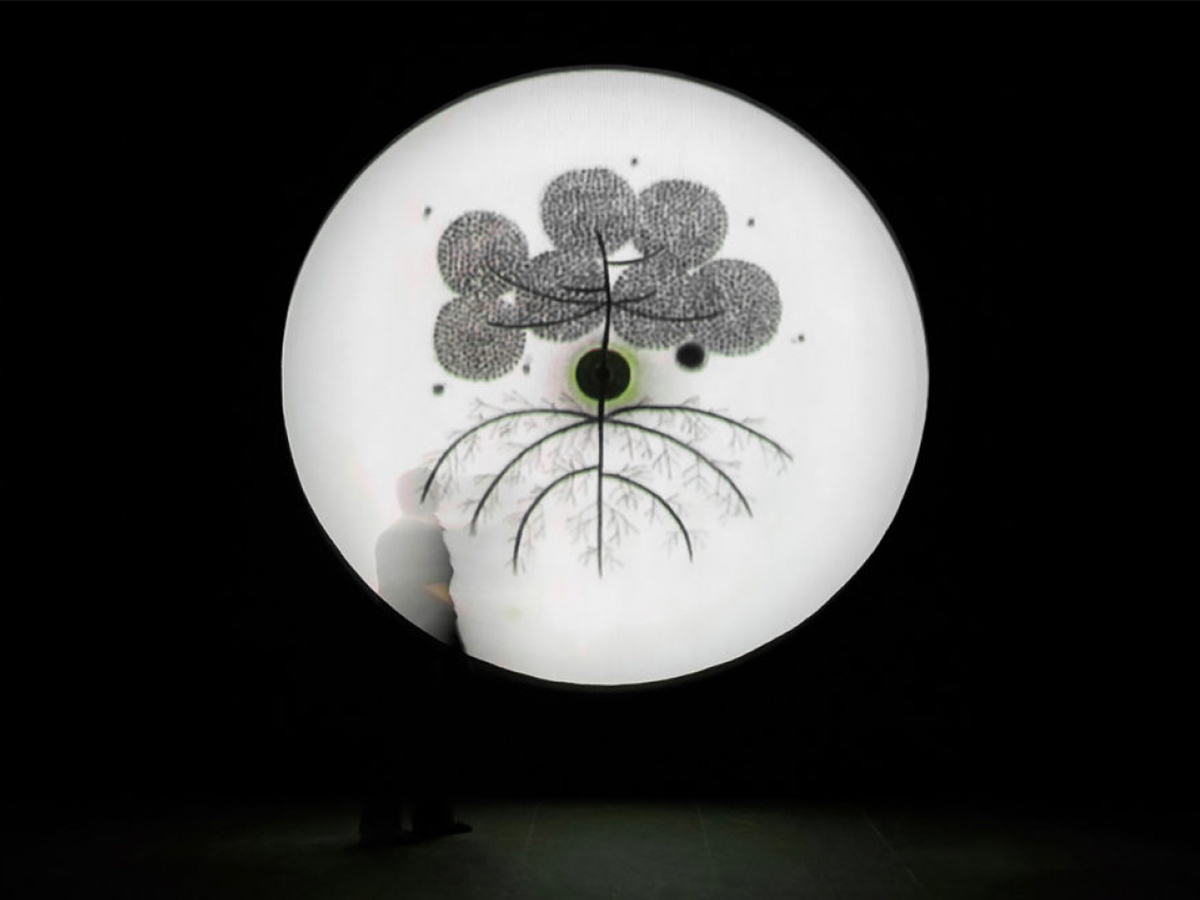 Black and white image of a white circle on a black background with a magnified plant and small sillhouette of a person in the white circle