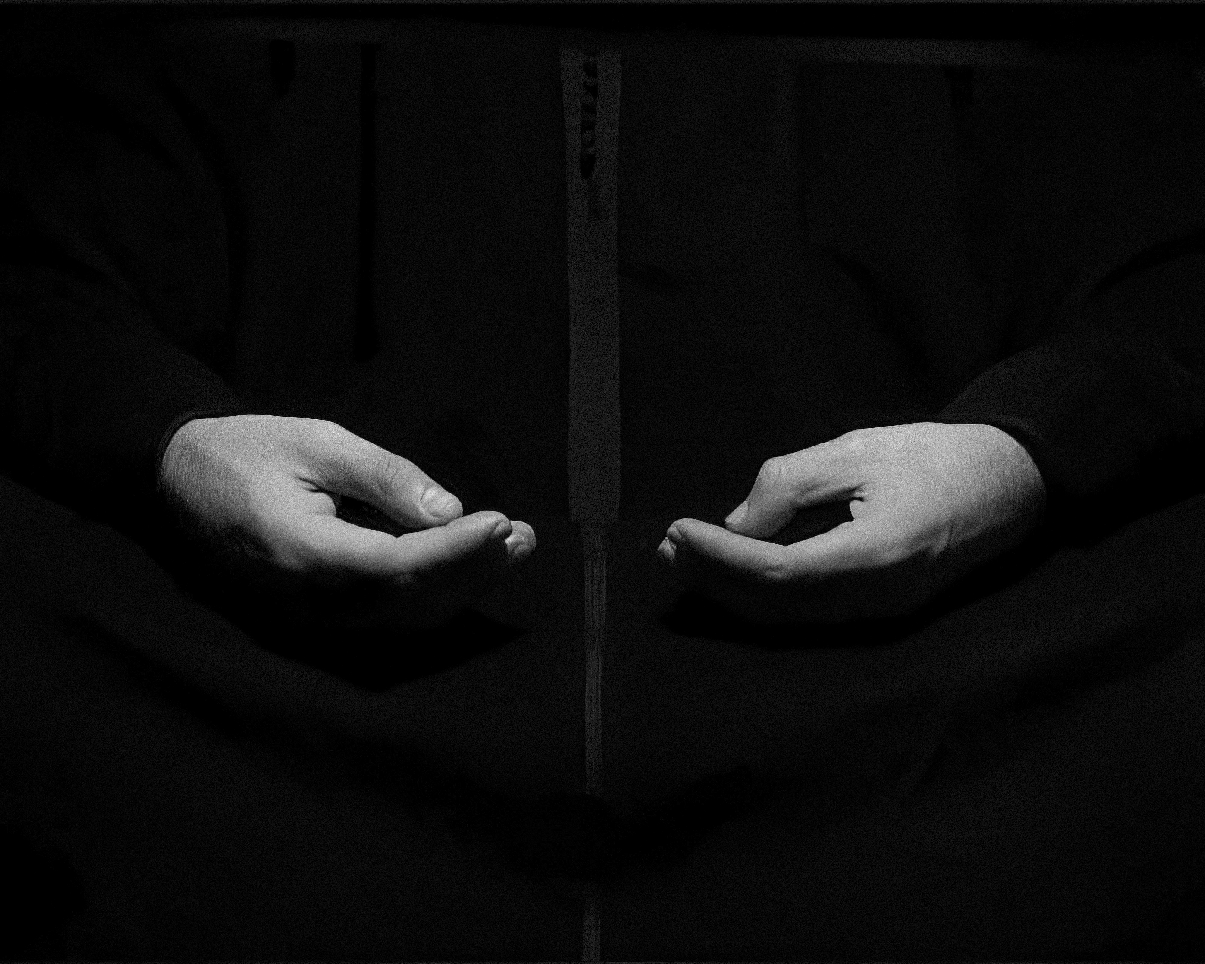 Photo of two hands cupped with fingers and thumbs closed with a black background