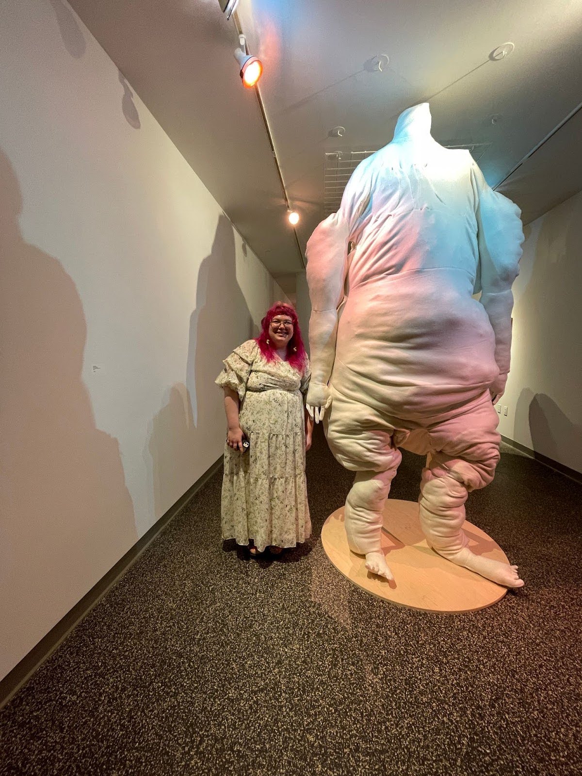 Lilly standing to the left their artwork – a large, white, anthropomorphic, fabric sculpture about twice their height.