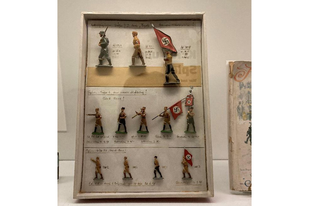 "glass case displaying tin toy soldiers dressed in Nazi garb"