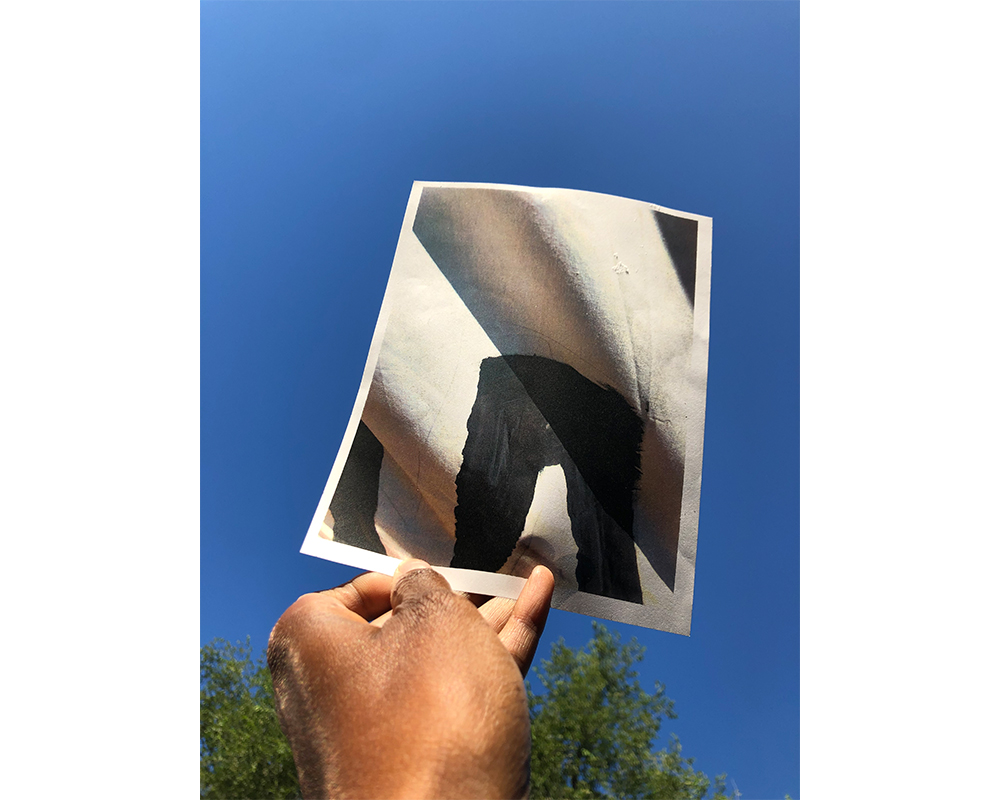 Amanda Wiliams's hand holding photo of a detail of a BLM banner outside Smith College droms/houses