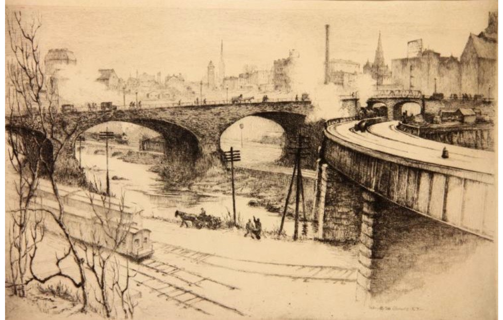 Pedestrian bridge over a river, railroad tracks and train alongside river, cityscape in the background.