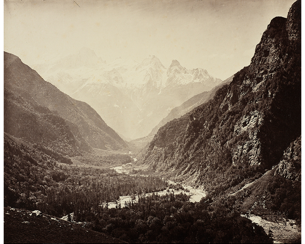 black and white image of three large mountains, with a body of water in the center