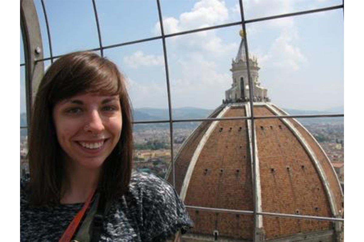 girl with brown hair and bangs standing in front of an Italian cathedral