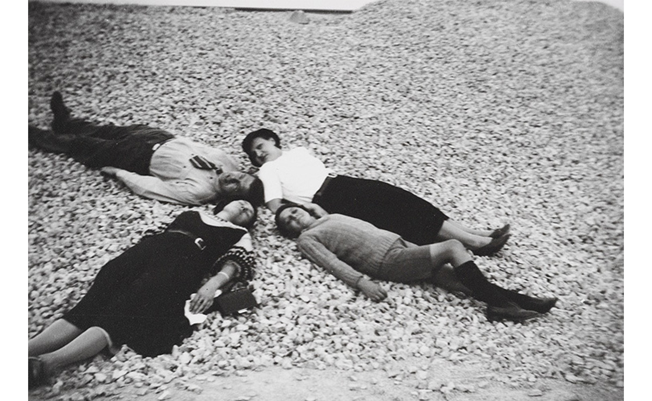 four people, three women and one man, lying on the ground with heads together
