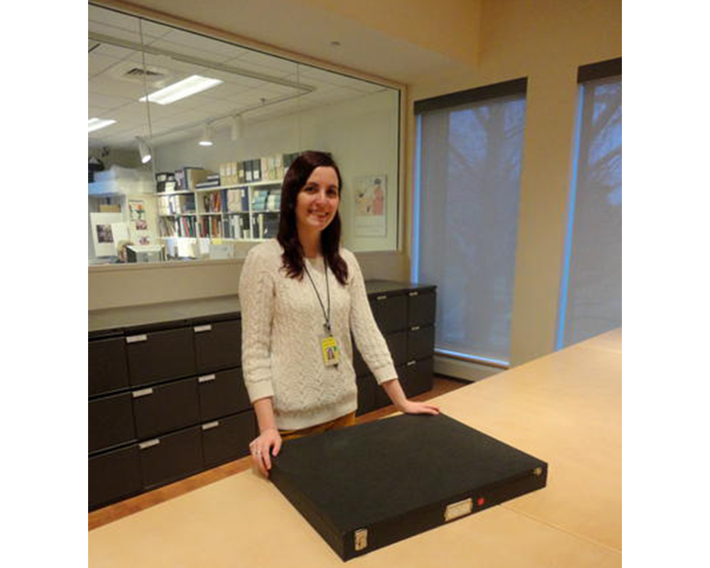 girl standing behind a wooden table with a black box on it