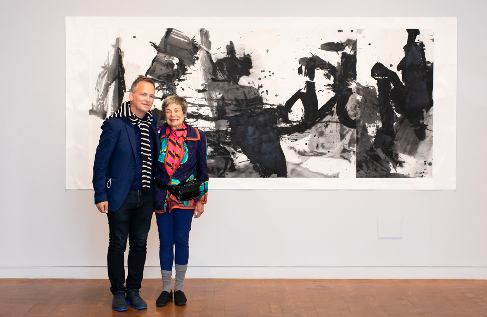 Two supporters of SCMA standing together in front of a painting. 
