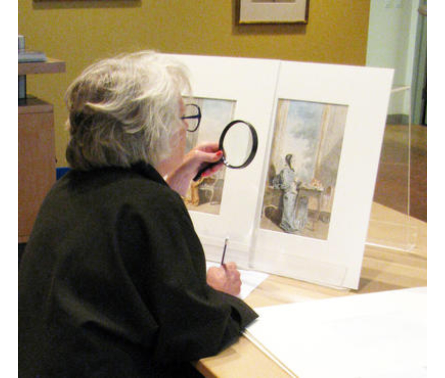 Suzanne uses a magnifying glass to examine works of art.
