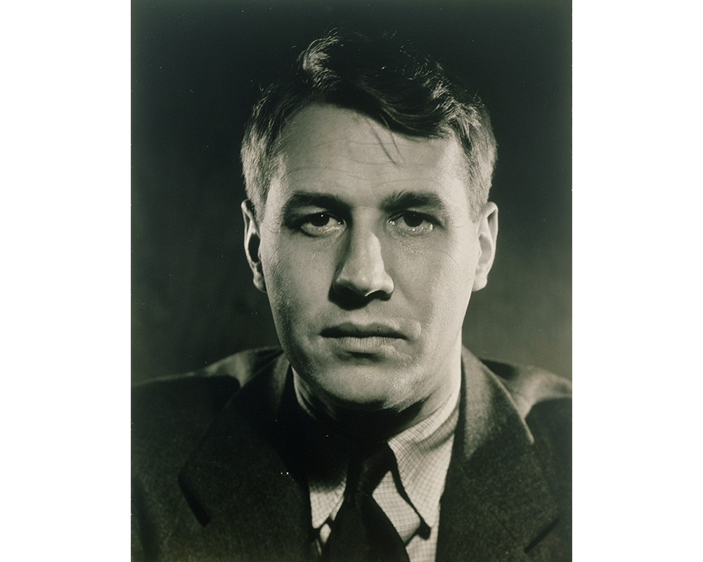 black and white bust portrait of man wearing suit, looking into the camera