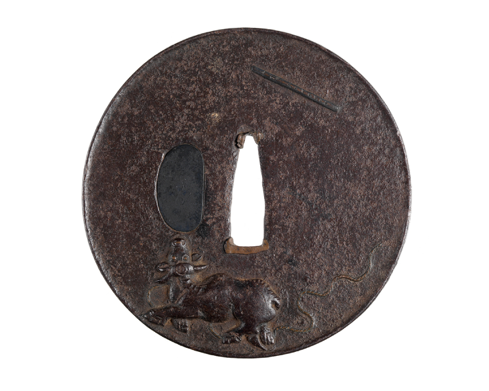 Flat disc with hole in center; relief of small bullock and flute on one side, scythe and curving lines on other side, shakudo and silver plug