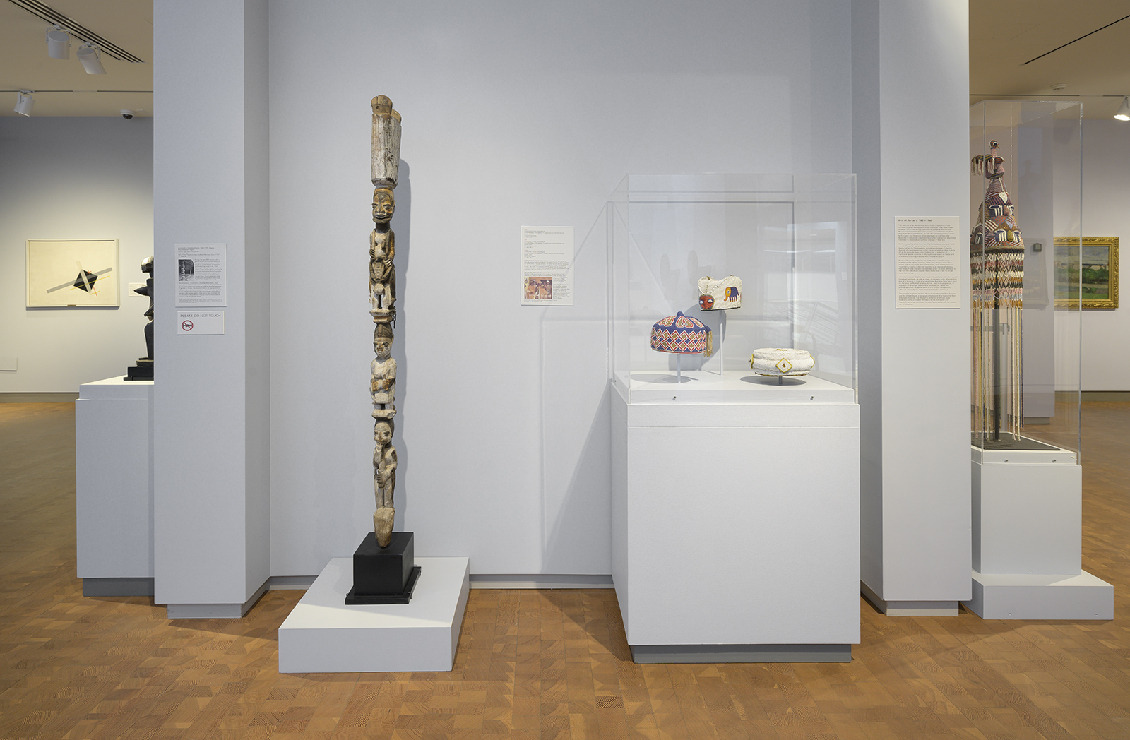 Finished gallery wall, with view of royal beaded crowns and a carved totem