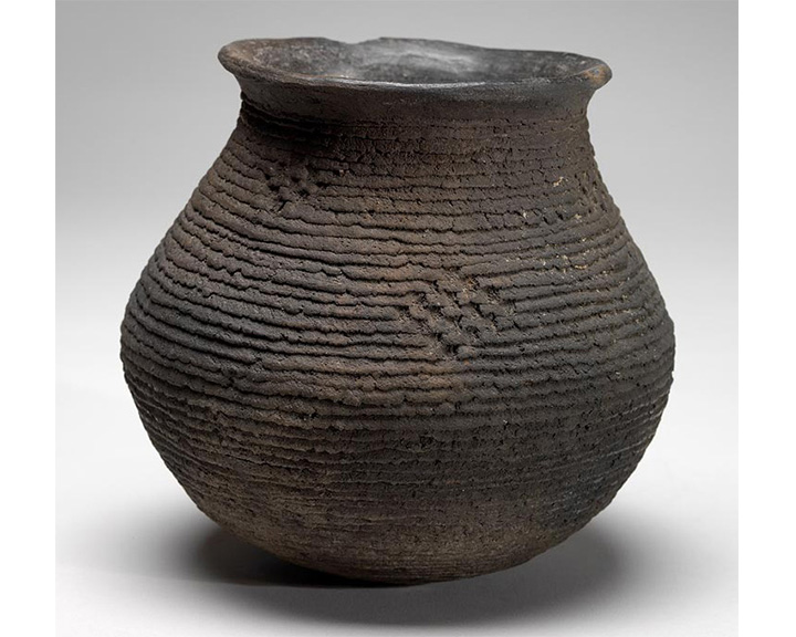 large vessel made from dark clay with imprinted woven design on surface