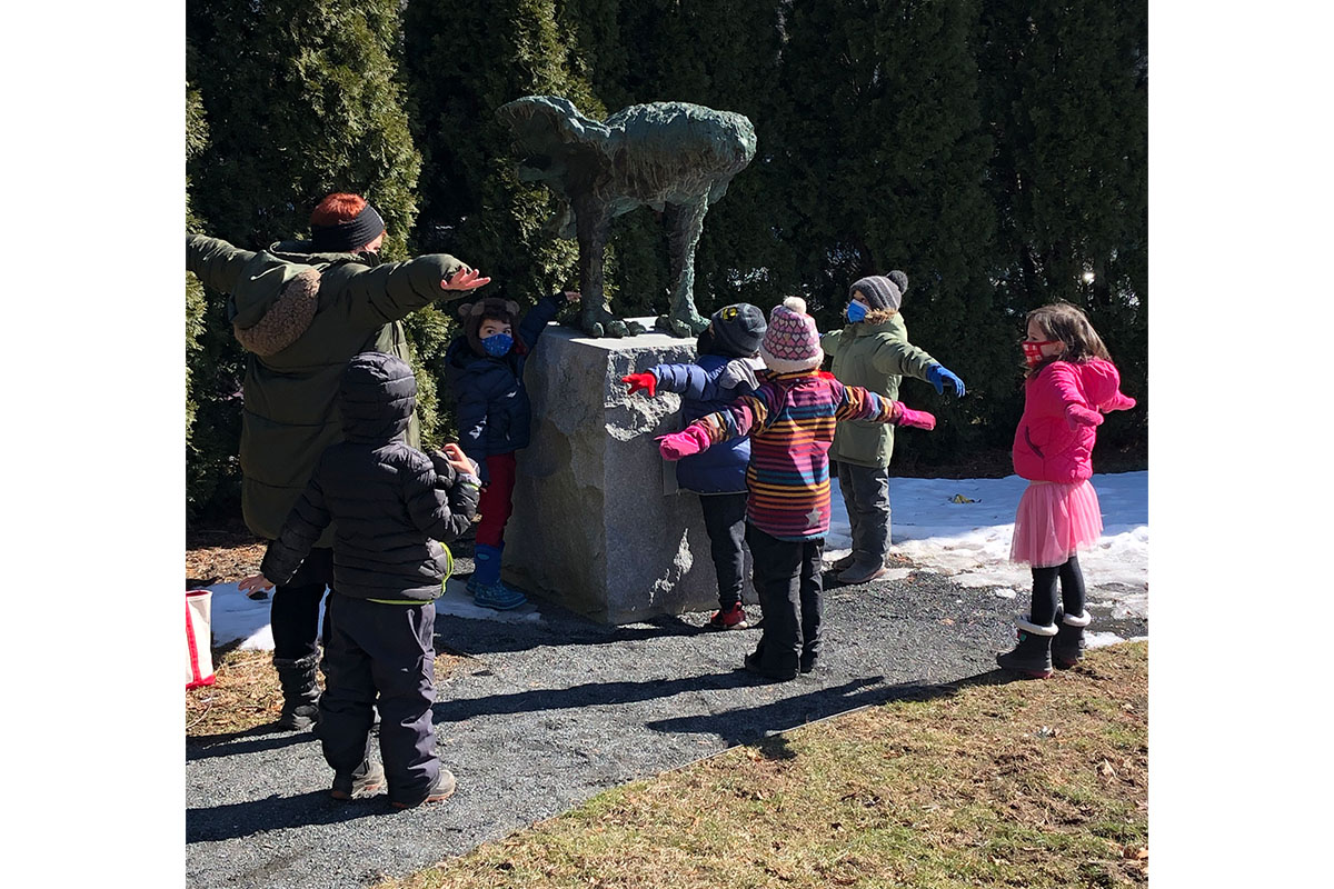 Children on outdoor tour looking at an Owl sculpture and mimicking its gesture