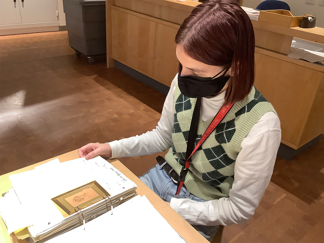 student sitting at desk looking through a binder