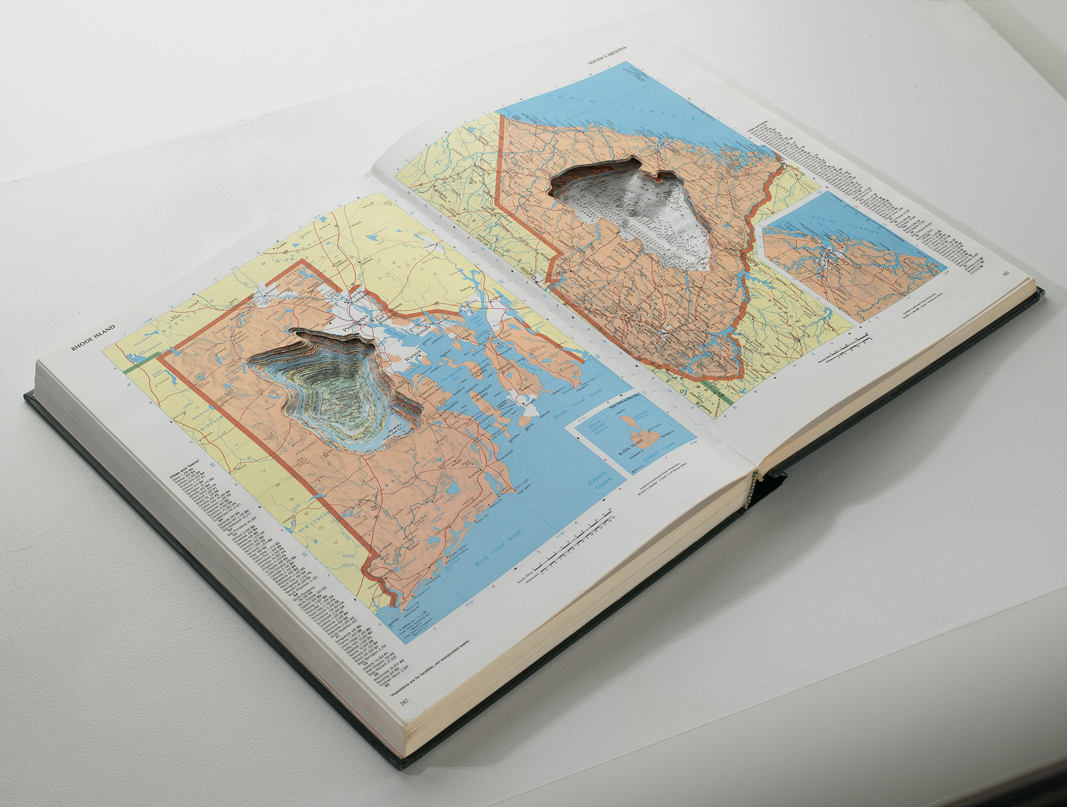 open atlas book with carved pages that look like topographical maps as they have depth