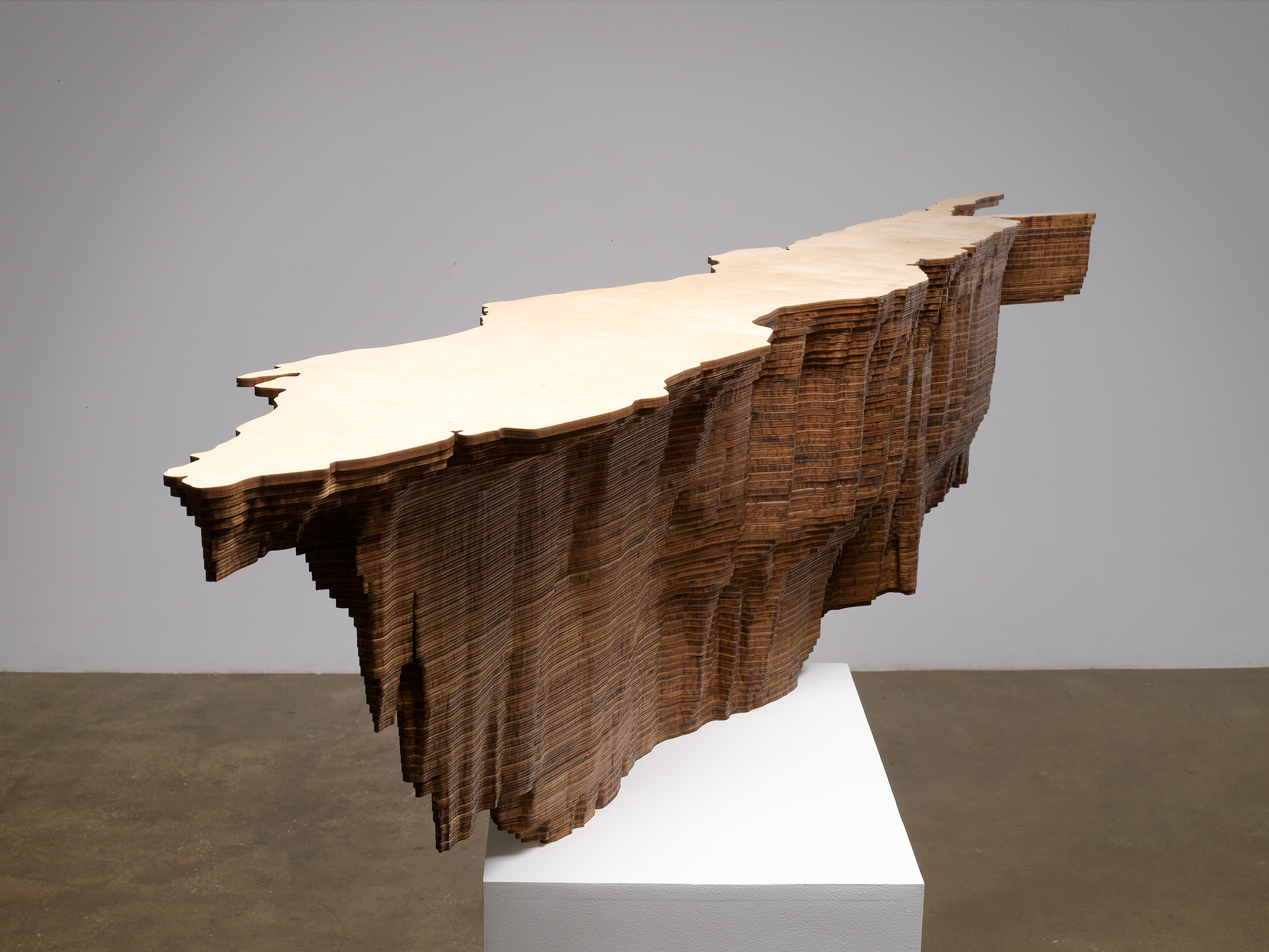 Wood sculpture on pedestal, carved on bottom like a topographical map