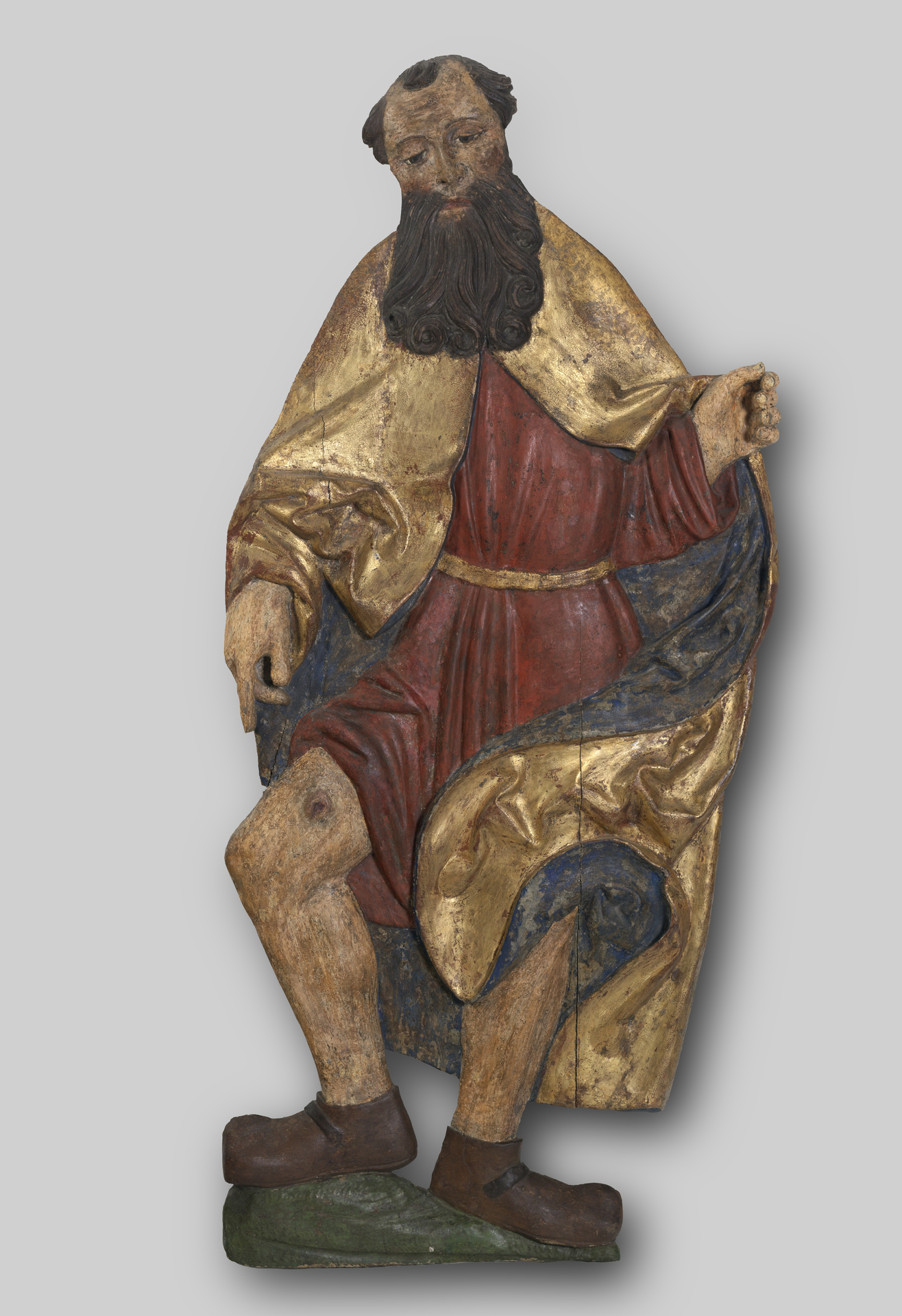 Painted wooden sculpture of a saint in a red robe and gilded gold cape. 