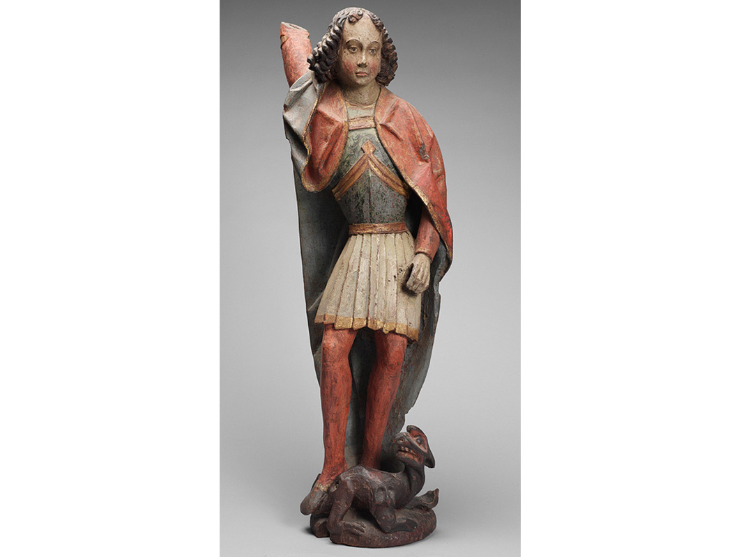 Painted wooden sculpture of a standing young man reaching over his head to grab something from behind