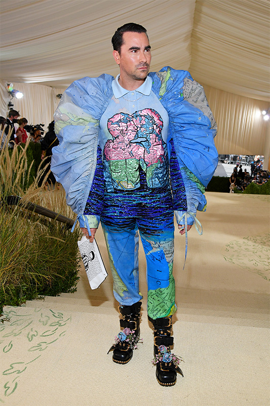 Dan Levy, a white man with slicked down brown hair, at the 2021 Met Gala, dressed in a blue John Anderson design with puffy sleeves inspired by Wojnarowicz's "Maps" 