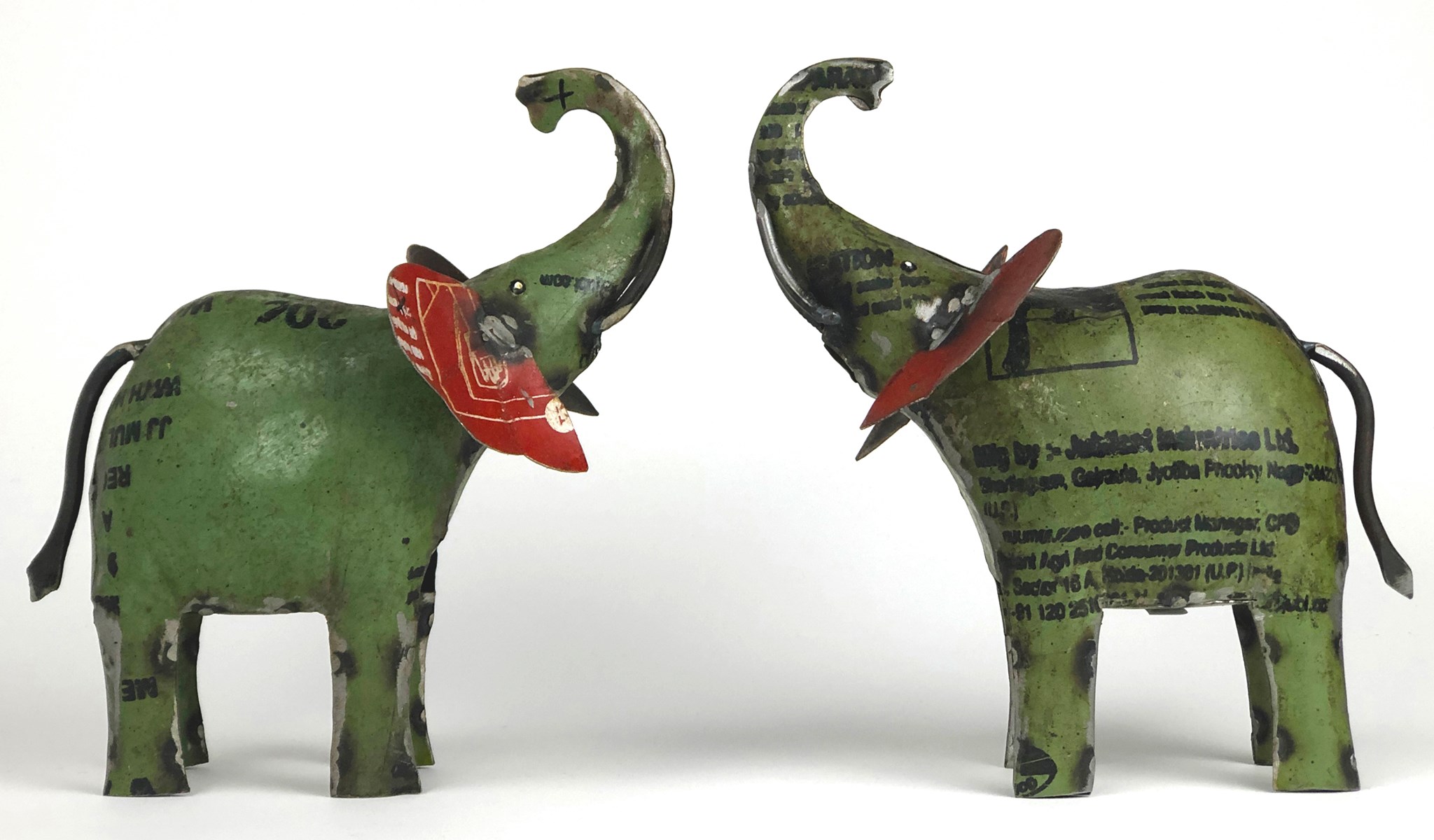 Two metal green elephant toys facing each other on a white background
