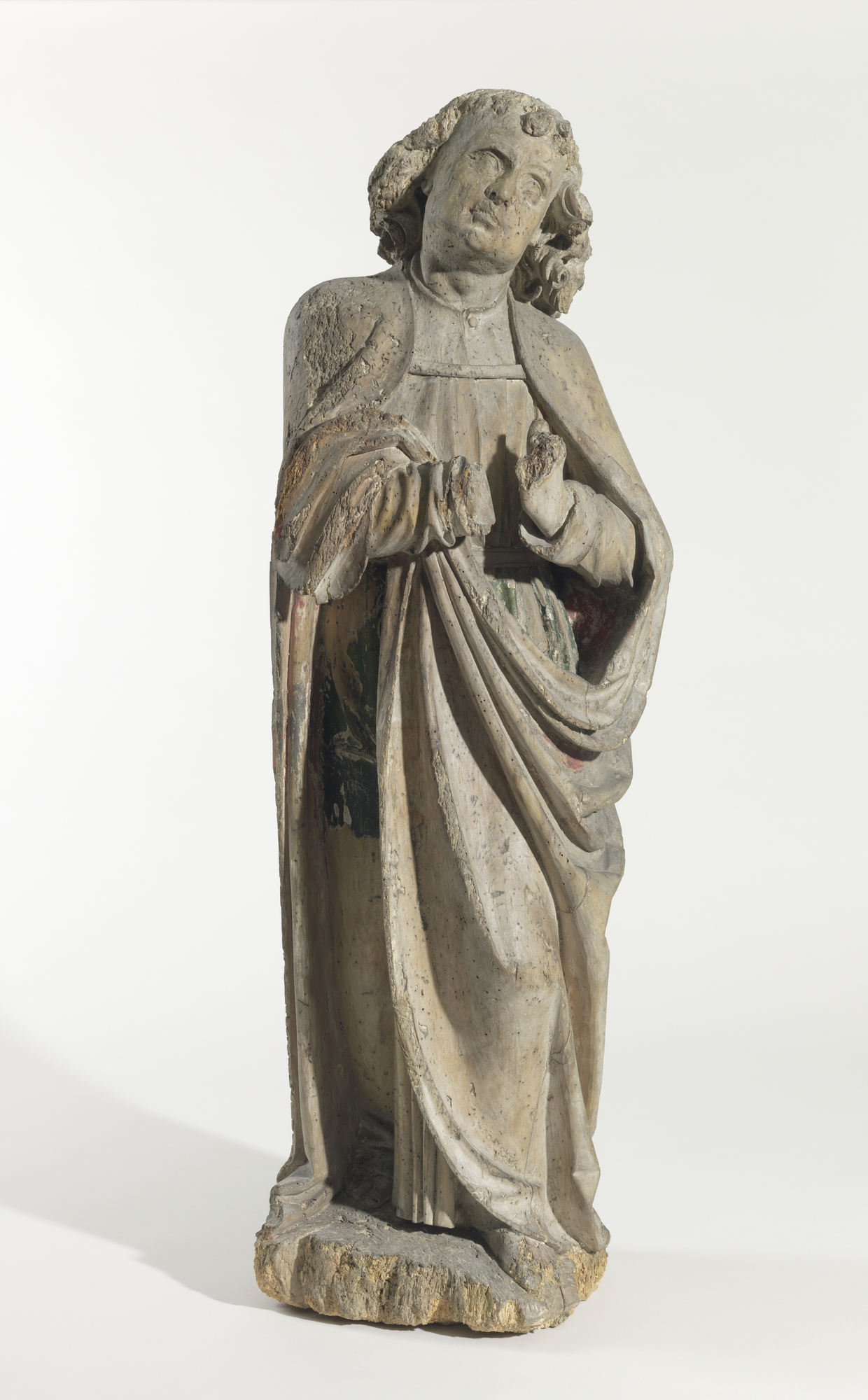 Carved wooden sculpture of a Saint in robes looking up in a motion of prayer.