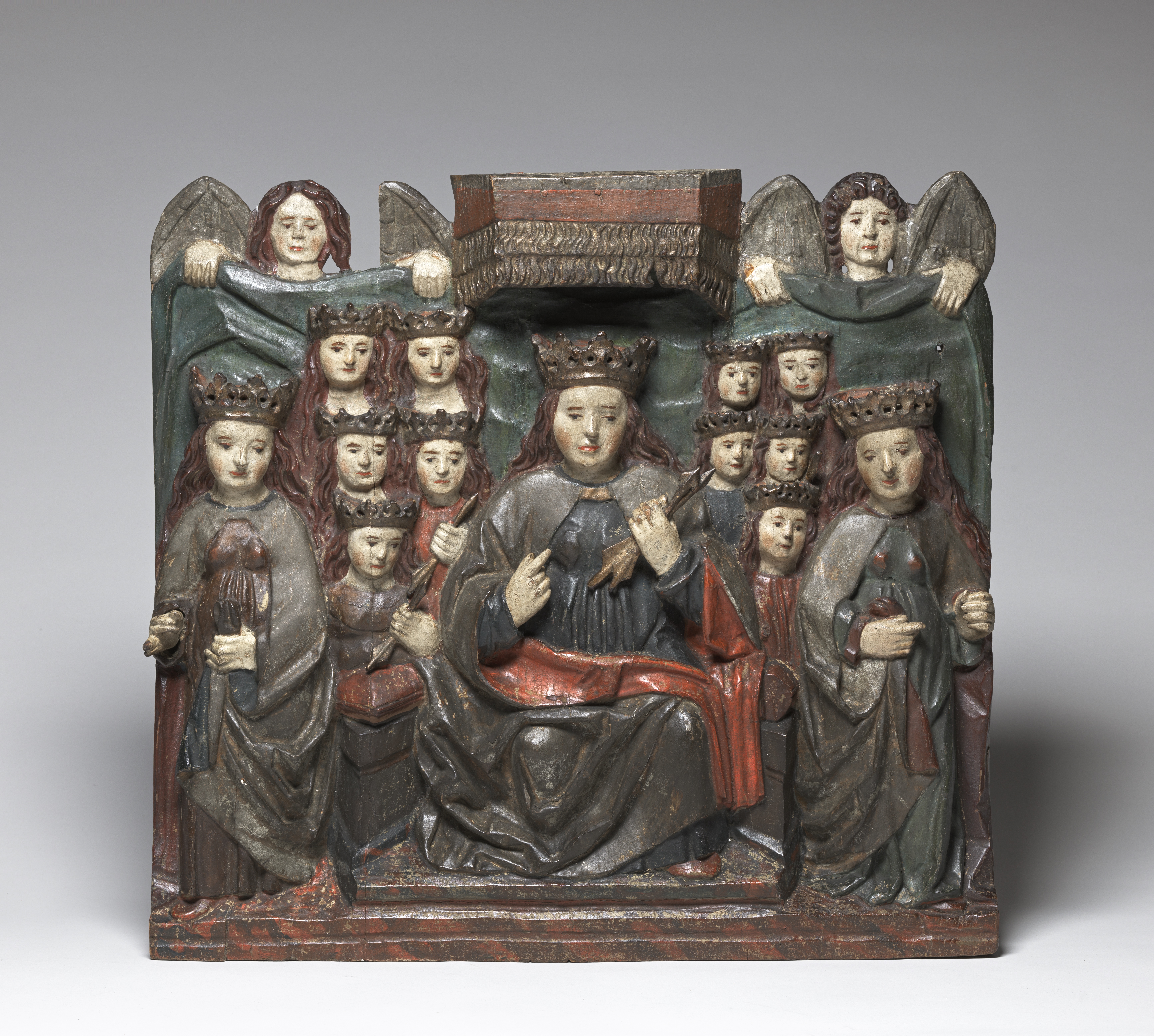Wooden sculpture of many women wearing cloaks and crowns. 
