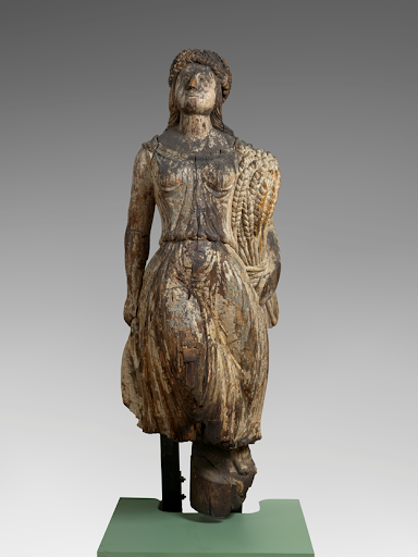 Carved wooden sculpture of a woman standing.