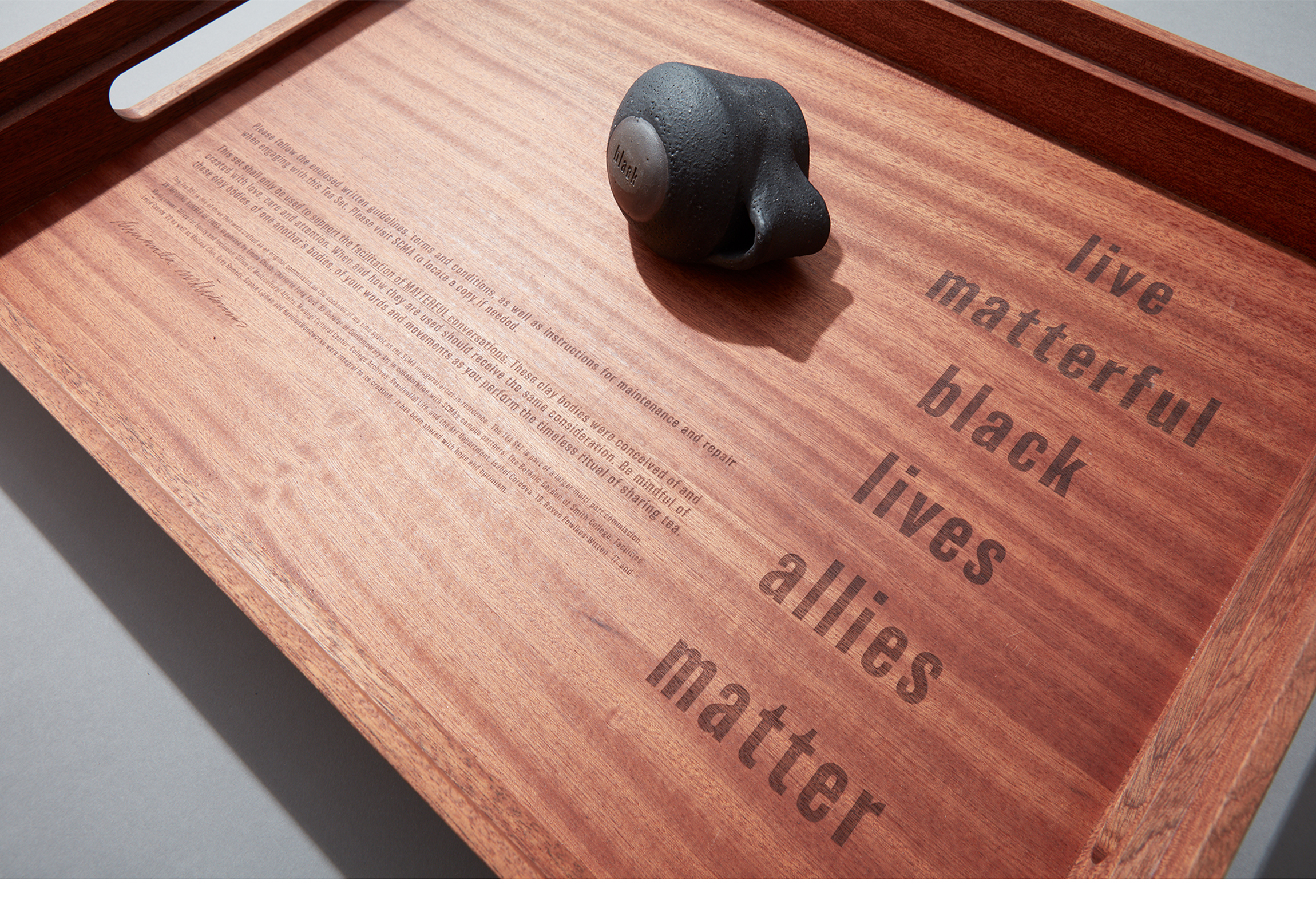 black glazed mug on its side on a wooden box with text on it