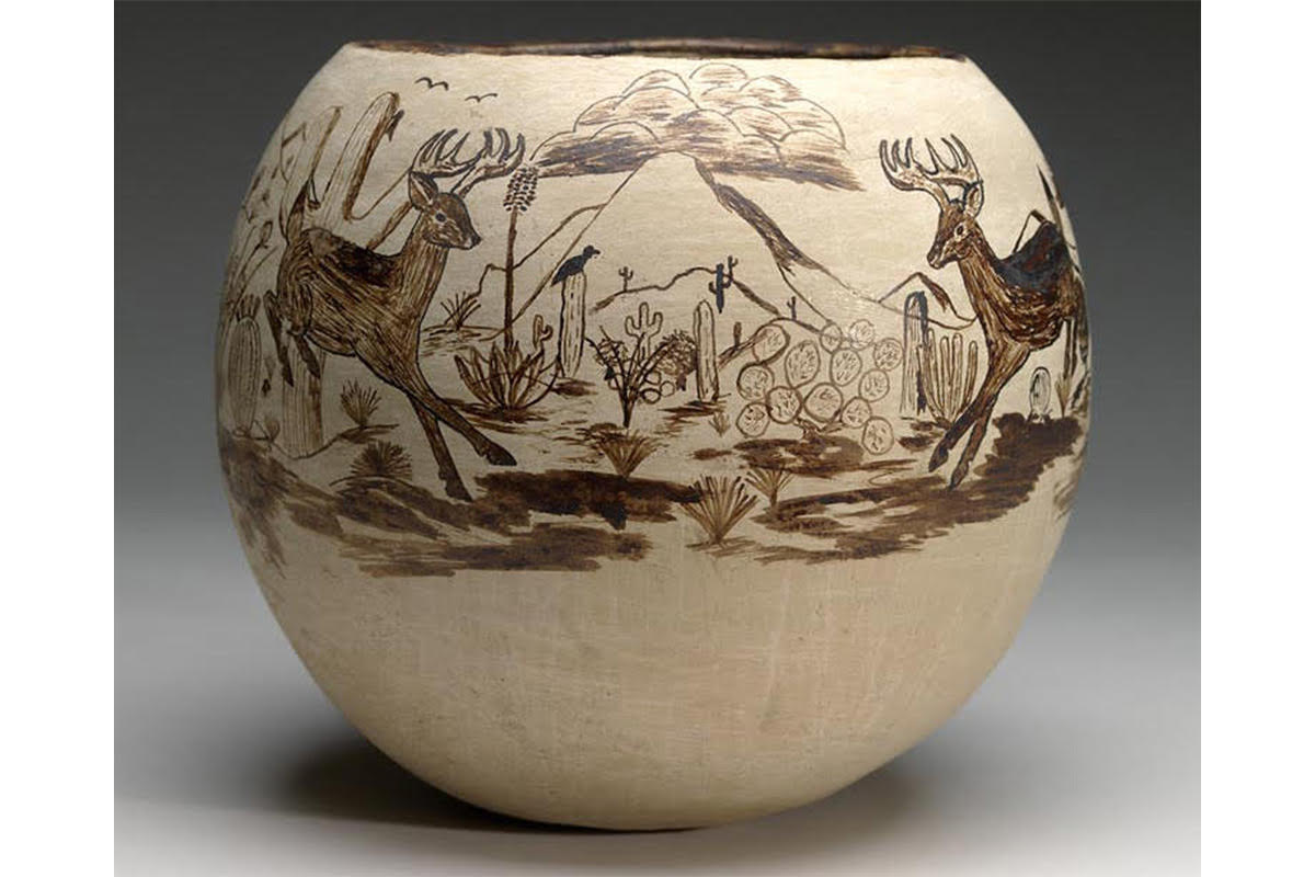 This pot is cream in color, with a black scene of animals (deer, bird) and plants (trees, cactus) painted onto the vessel. Mountains and clouds are also featured. A black line encompasses the rim. Like other Tohono O'odham ceramics, a large portion of the vessel is left painted white with little decoration.