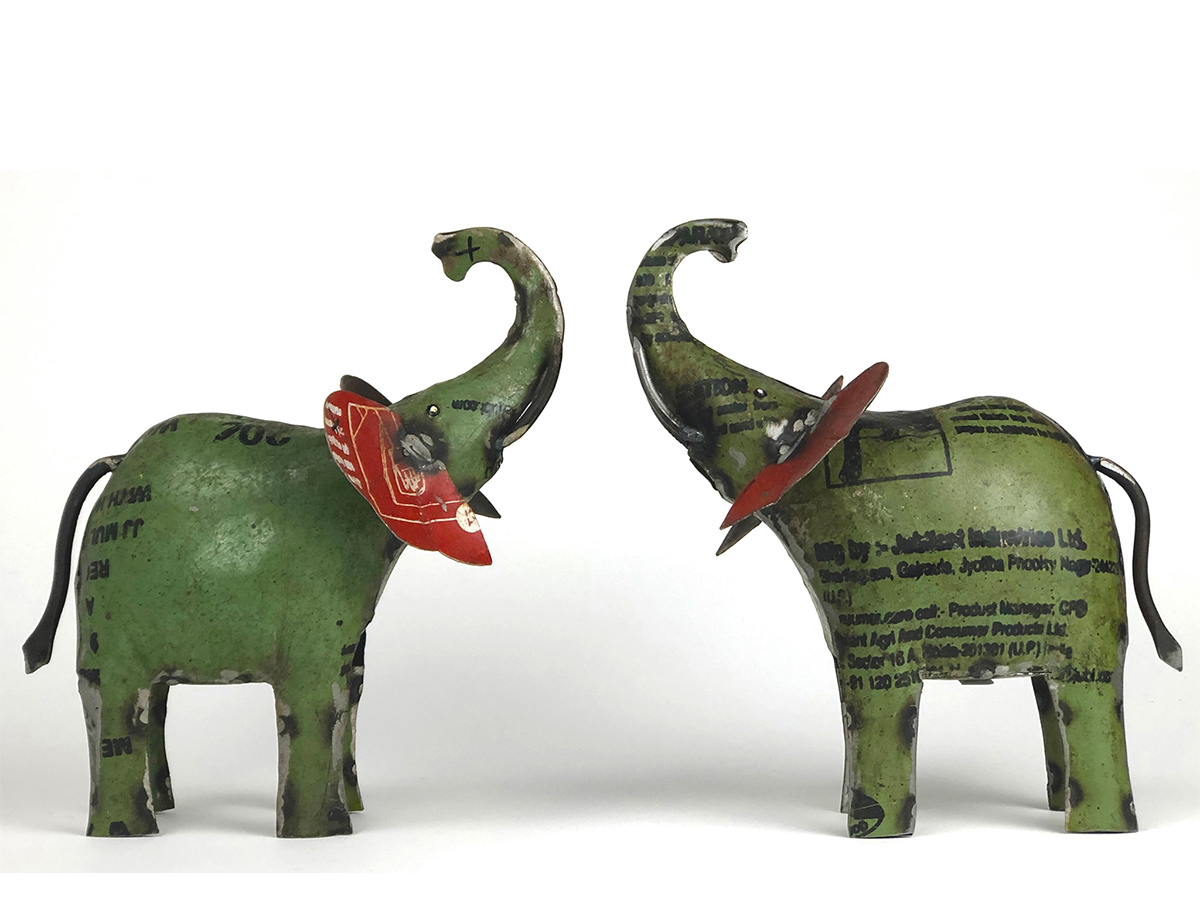 Two green tin elephants in sideview trunk to trunk