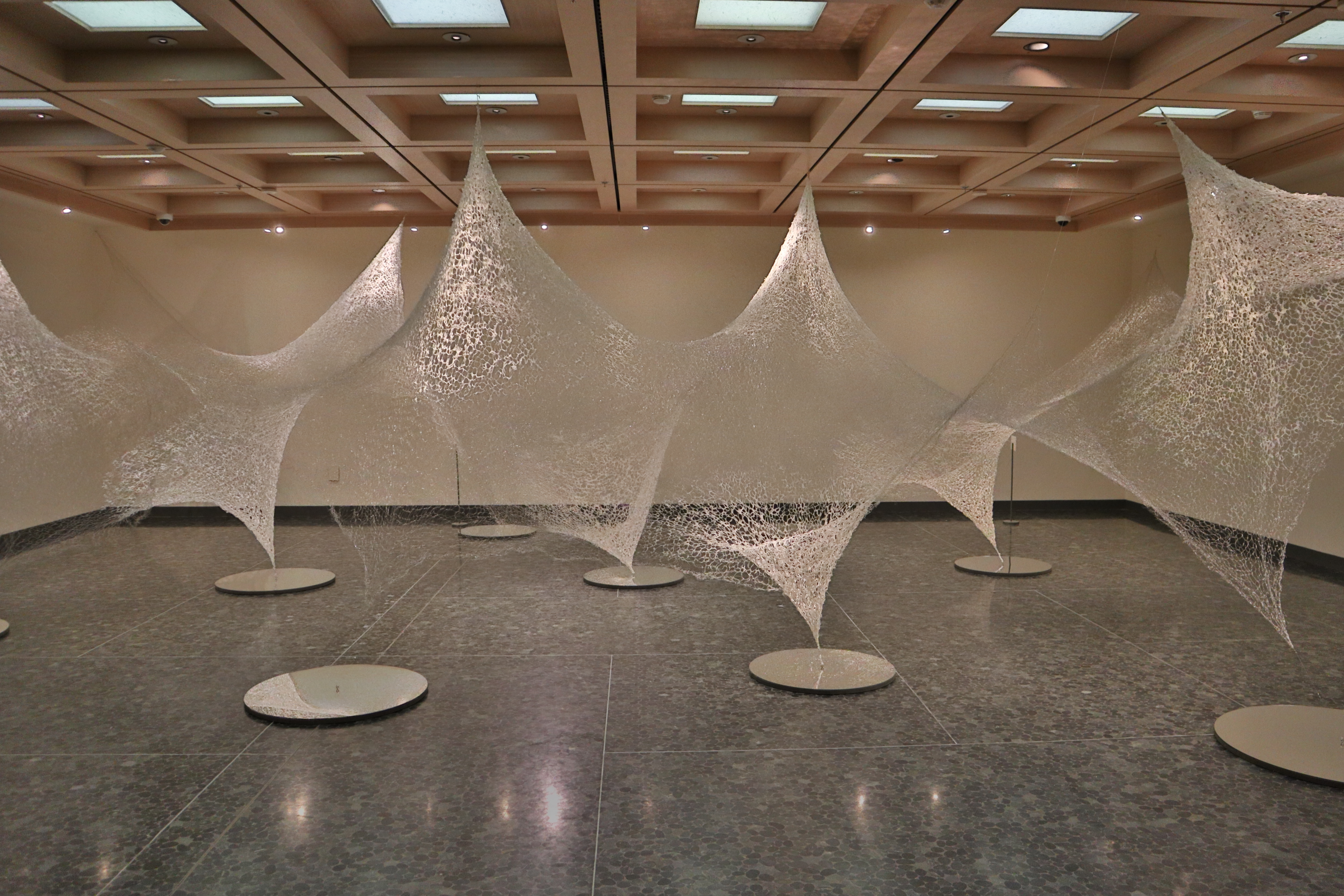 Gallery image with knit fishing lines that look like webs hanging from the ceiling.