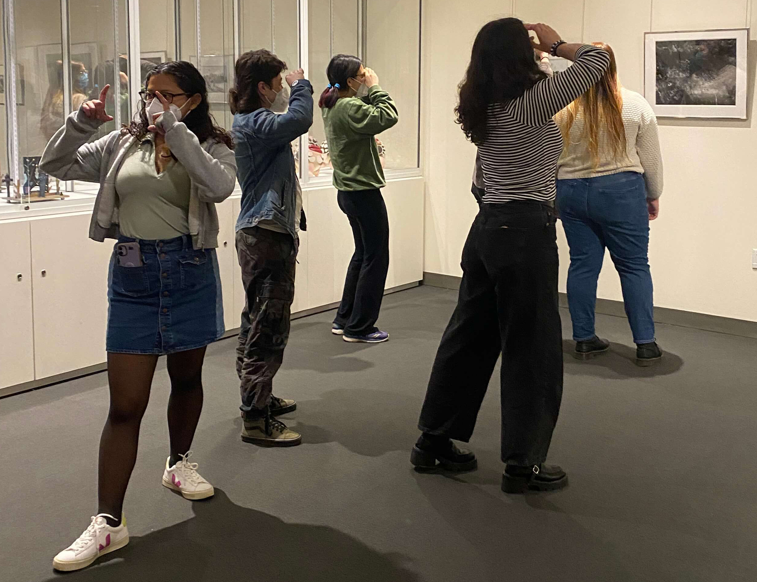 Five students standing in a gallery with hands in positions of looking through an invisible frame