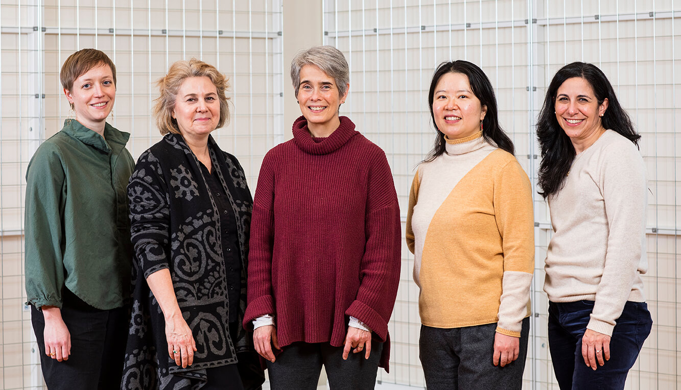 Five women posing for a standing photo, all looking at the camera