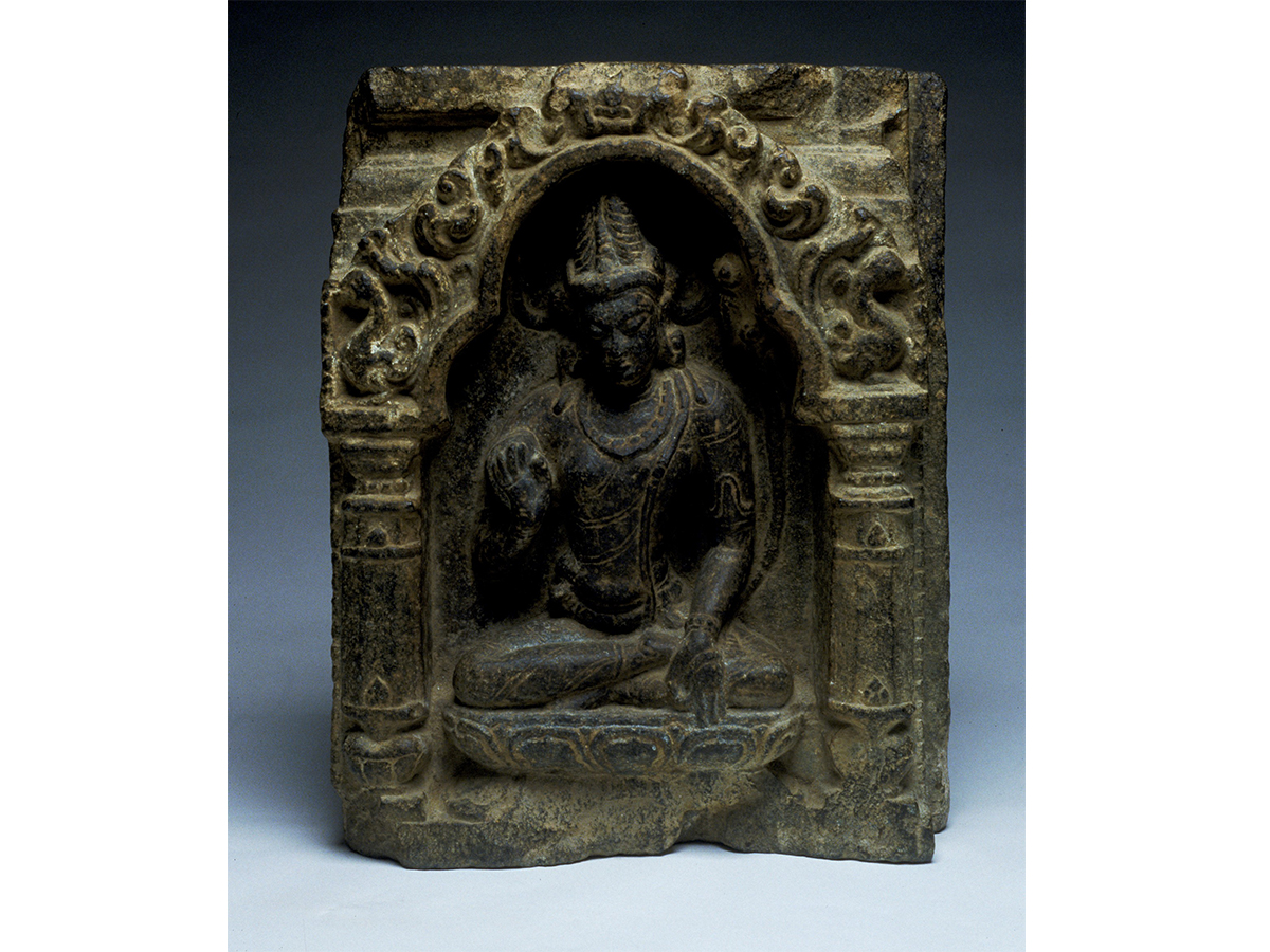Ancient stone carving of Buddha sitting within a temple arch