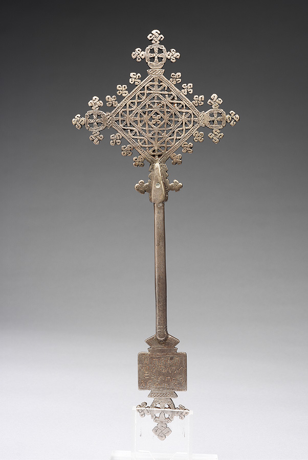 Image of a silver Ethiopian cross with long stem and inscription at the bottom