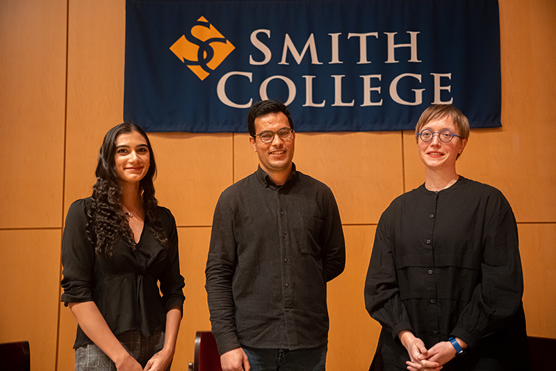 Three people posing while standing in front of a banner with text Smith College