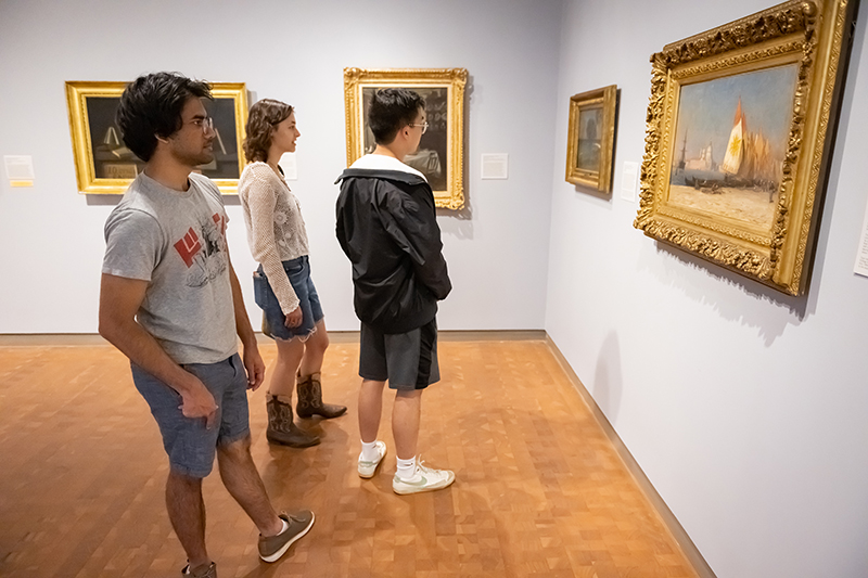 Three young adults looking at art in a gallery