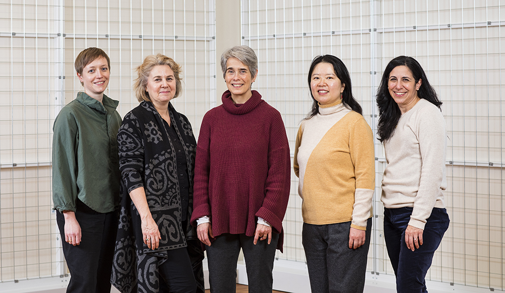 5 People posing in a line with hands by their sides