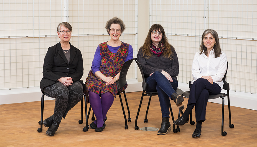 Four people sitting in chairs looking at the viewer