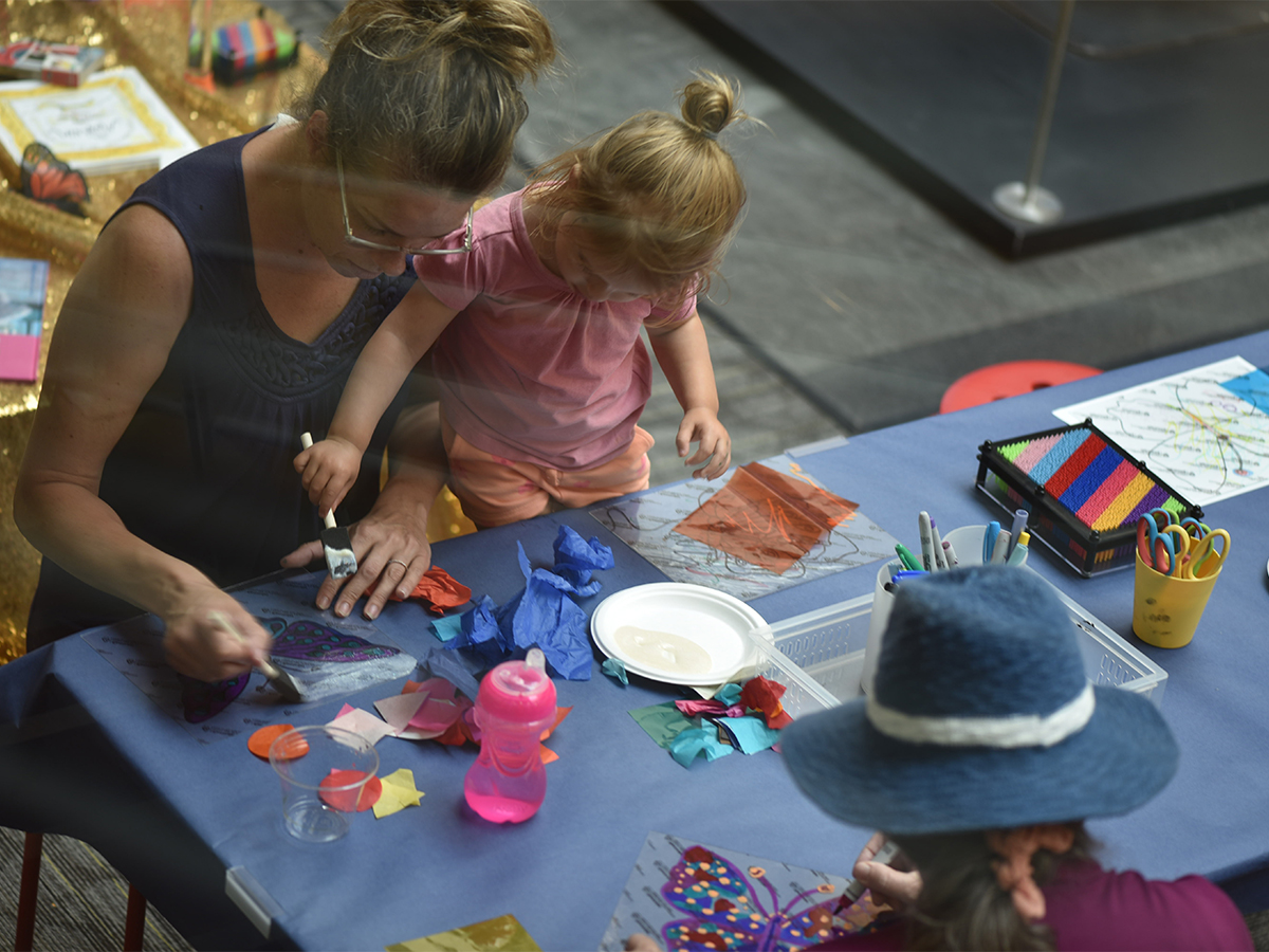 birds eye view of a woman with child making art at a table along with someone in a hat sitting across from them