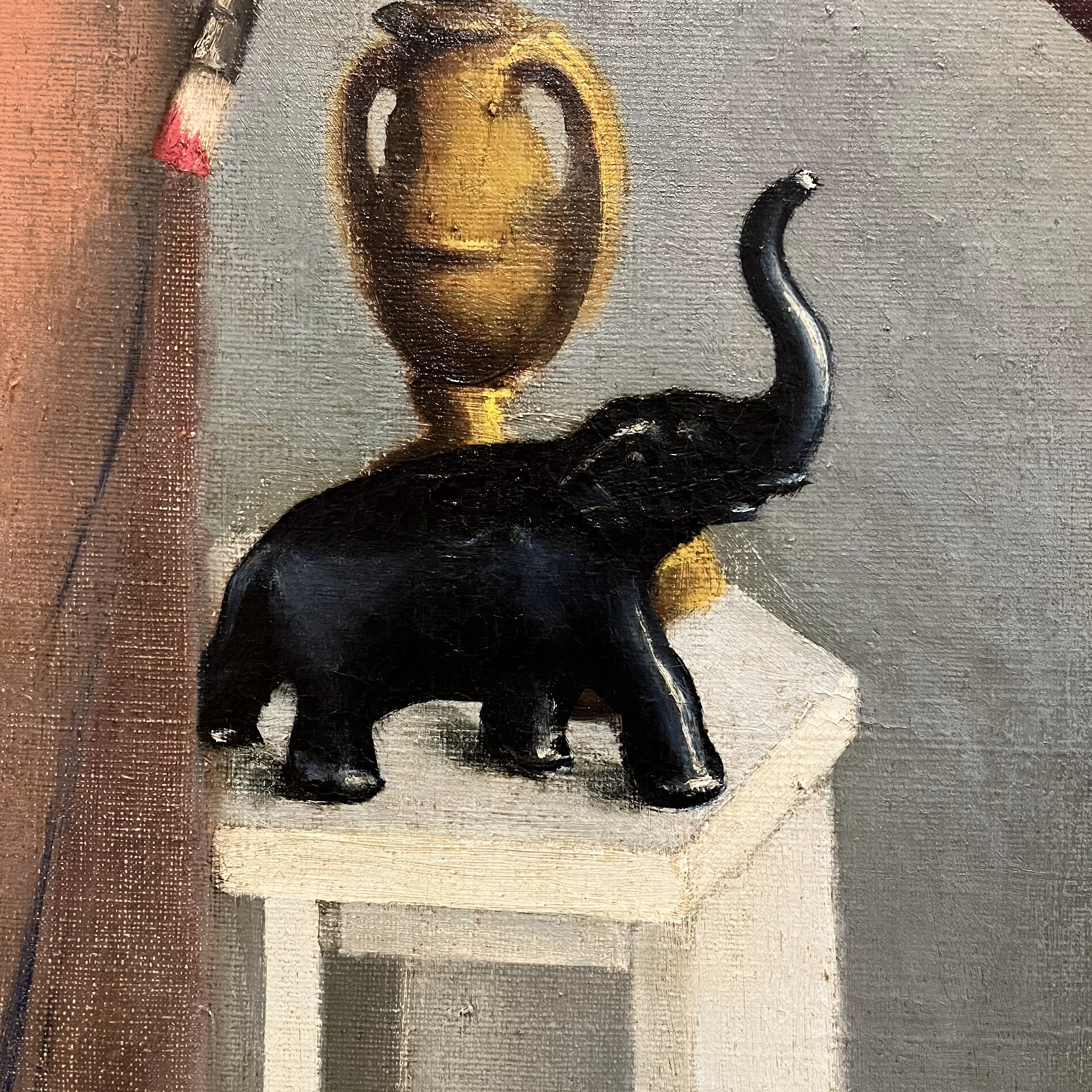 elephant statue on a white side table with a gold vase behind it