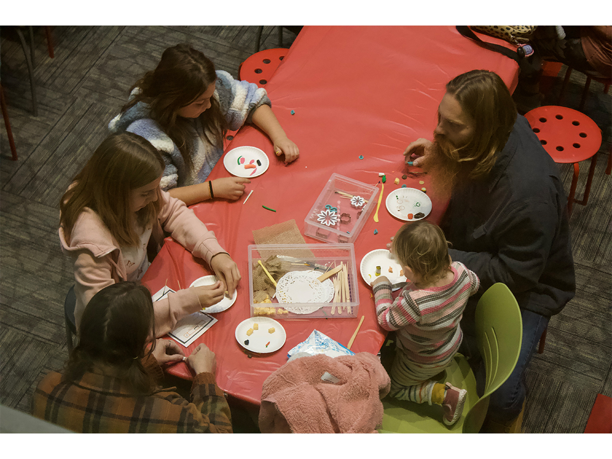 Birds eye view of five people sitting at a table making art