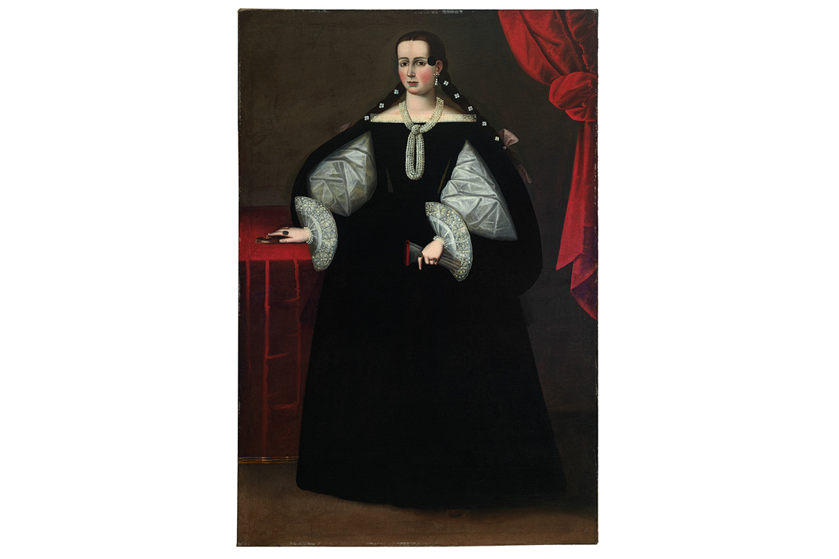 Full-length portrait of a woman in a black dress with white lacy sleeves. She wears ornate pearl jewelry and stands with her right hand placed on a box. A red curtain drapes behind her in the upper right corner.