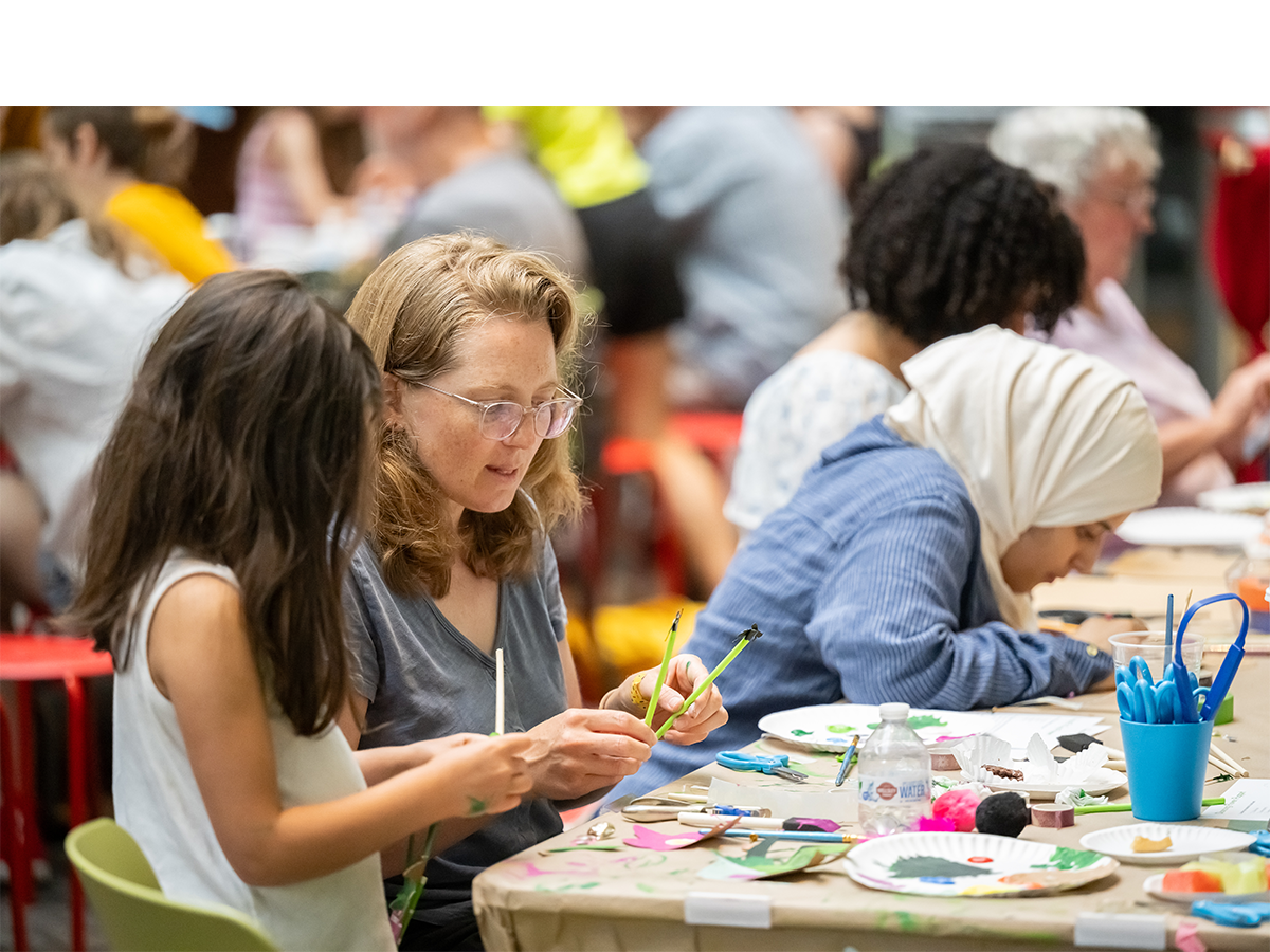 Crowd of people of all ages crafting art with paint and paper