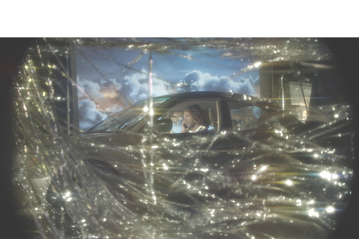 Figure in a car on the phone behind gold streamers